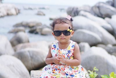 Baby girl wearing sunglasses on rock