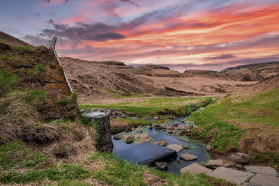 Turf house and geothermal spring in hrunalaug against dramatic sky during sunset