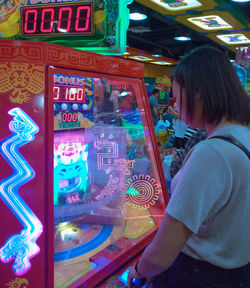 Side view of woman looking at illuminated nightclub