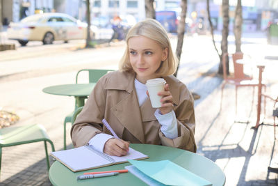 Portrait of young woman sitting on table