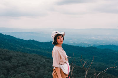 Young woman standing against mountains against sky