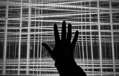 Close-up of silhouette hand touching illuminated light