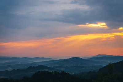 Scenic view of mountains against dramatic sky during sunset