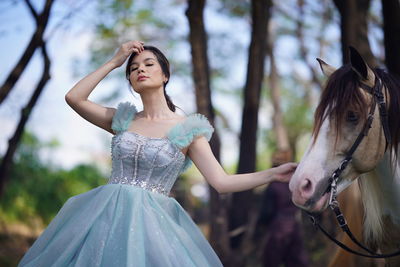 Portrait of a beautiful woman with a horse in the forest background.