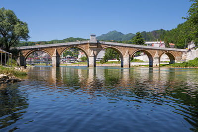 Arch bridge over river against clear sky