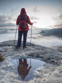 Extreme trail walker above canyon full of heavy mist. full lengh female body mirroring in water pool