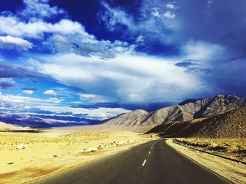 Road by mountains against blue sky
