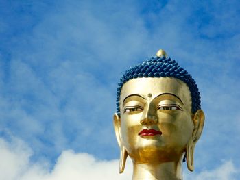 Low angle view of buddha statue against sky