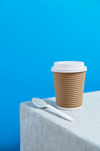Reusable cup on white table with white plastic cap and spoon