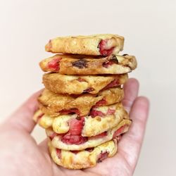 Cropped hand holding cookies against wall