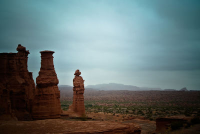 Rock formations on landscape against cloudy sky