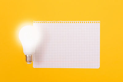 Close-up of light bulb against yellow background