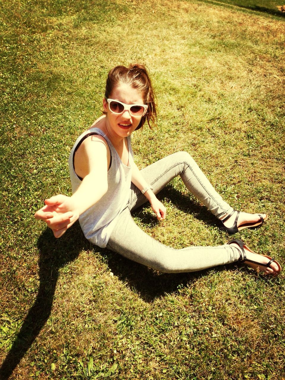 grass, person, high angle view, full length, childhood, lifestyles, leisure activity, sitting, casual clothing, portrait, looking at camera, field, elementary age, sunlight, holding, green color, grassy, day