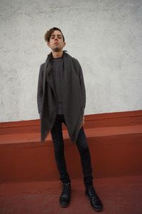 Portrait of young man standing against wall