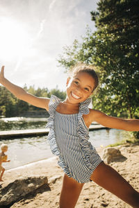 Portrait of happy girl with arms outstretched enjoying during sunny day on vacation