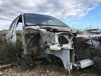 Abandoned car on field against sky