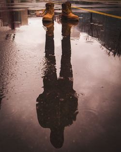 Low section of person standing on puddle in city during rainy season