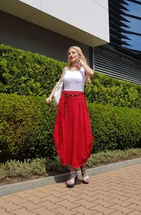 Full length of fashionable woman standing on footpath by plants