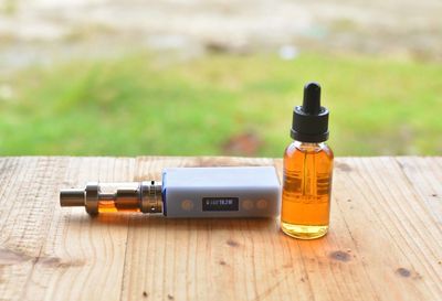 Essential oil in bottle by electronic cigarette on table