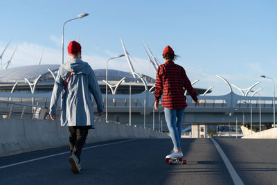 Rear view of people walking on road against sky