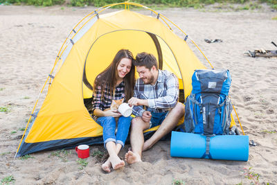 Happy friends sitting on tent