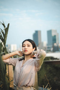 Young woman standing against sky