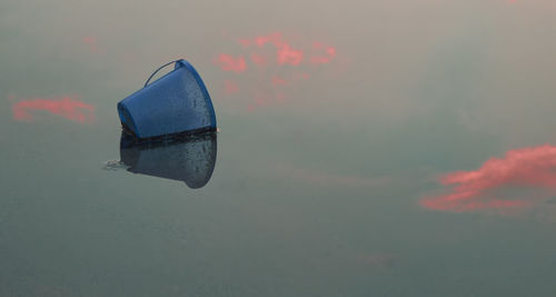 Close-up of bucket floating on lake during sunset