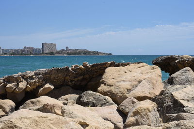 Rocks on shore by sea against sky