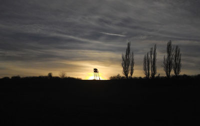 Silhouette trees on field against sky during sunset