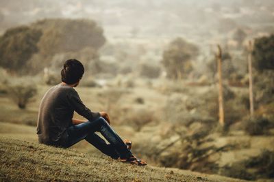 Side view of boy sitting on land