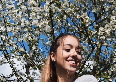 Young woman smiling against flowering tree