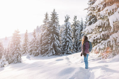 Rear view of man walking on snow covered landscape