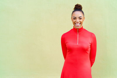 Portrait of young woman standing against wall