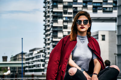 Portrait of young woman wearing sunglasses standing against sky