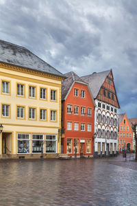 Buildings by river against sky