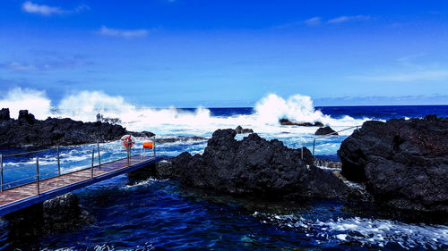 Panoramic shot of rocks in sea against blue sky