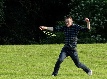 Full length of man walking while throwing plastic disc on grass