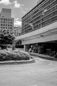 Empty road by buildings against sky in city