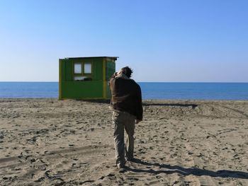 Rear view of man on beach against clear sky