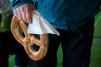 Midsection of person holding pretzel