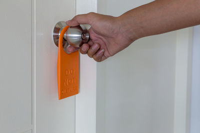 Cropped hand of woman holding do not disturb sign at door