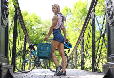 Full length portrait of smiling young woman on bicycle