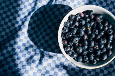 High angle view of blueberries in bowl on dish towel