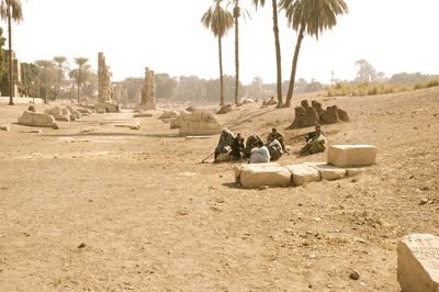 Panoramic view of people relaxing on field against clear sky