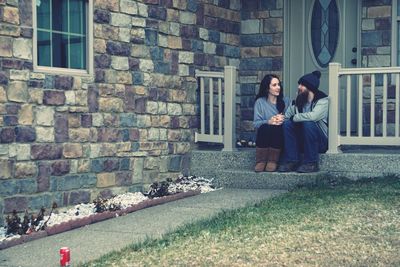 Young couple sitting on brick wall