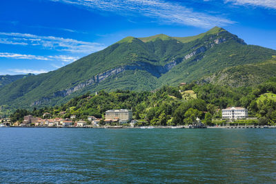 Scenic view of sea by mountain against sky