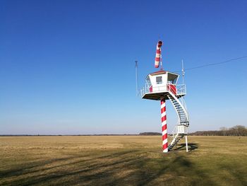 Traditional windmill on field against clear blue sky