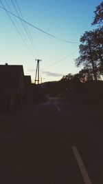 Electricity pylons on road at sunset