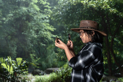 Girl examining rocks using a magnifying glass in tropical forest after rain