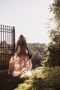 Rear view of woman standing against trees